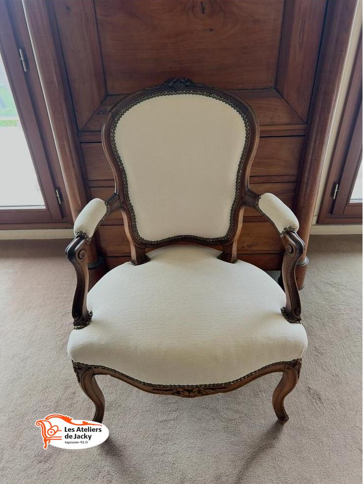 Fauteuil cabriolet de style Louis XV restauré avec un nouveau tissu clair et une finition traditionnelle.